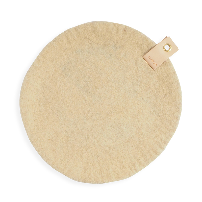Aveva's round sand seat cushion made with naturally dyed wool, and with a detail in Swedish leather with a metal eye for hanging.