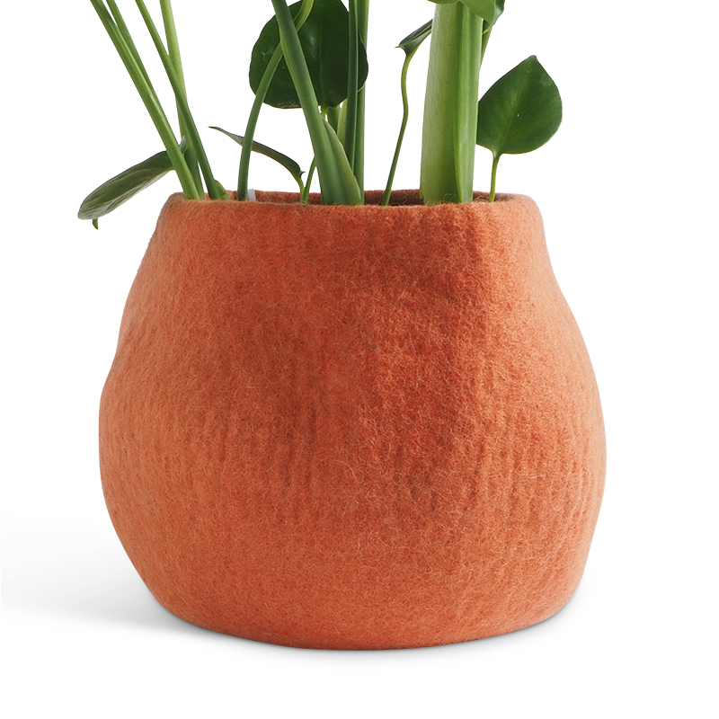 Large rounded flower pot in color terracotta, made of wool, with a plant inside.