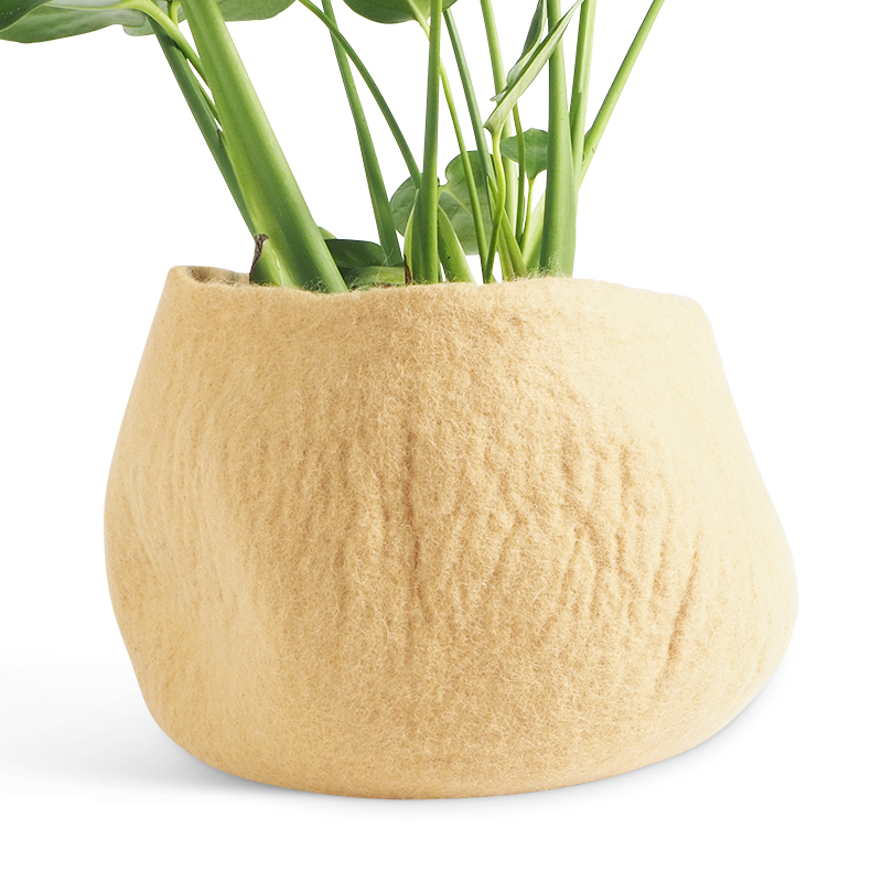 Large rounded flower pot in color sand, made of wool, with a plant inside.