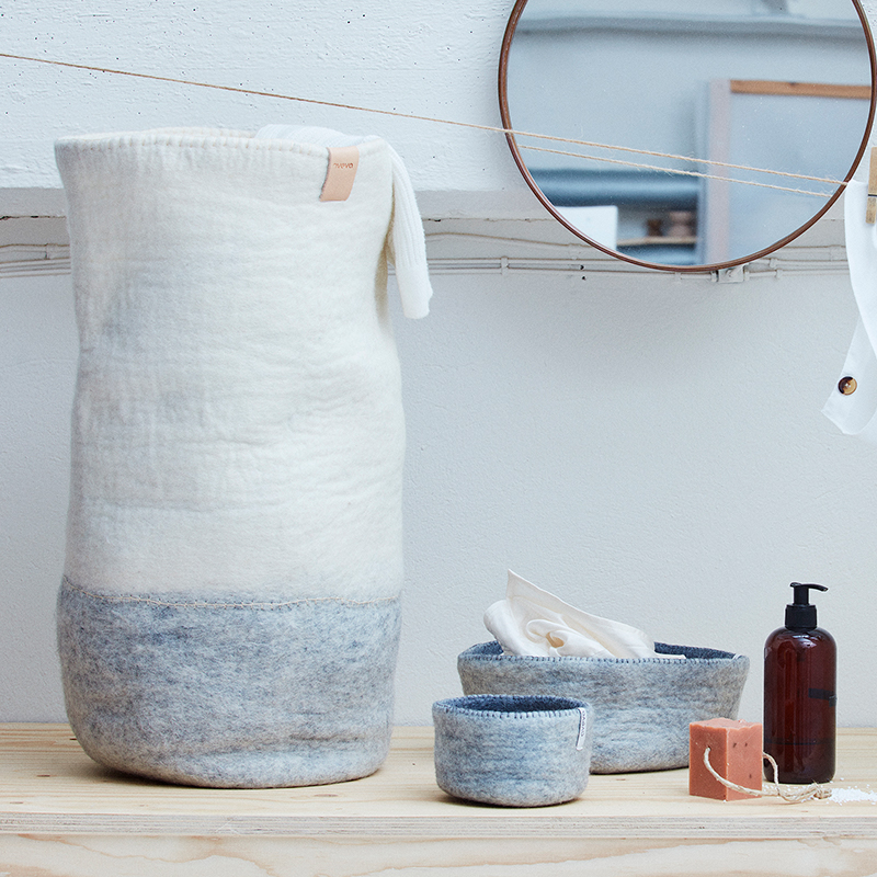 Tvättkorg i grått och vitt med tvättartiklar runt om.