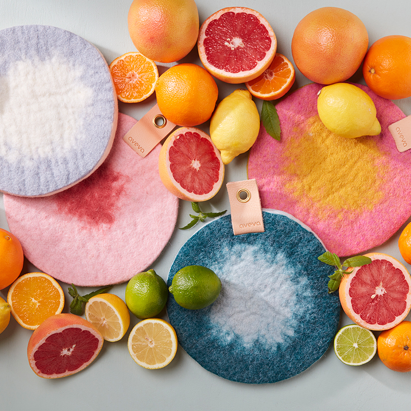 Round trivet in ombre with placed citrus fruits next to the trivet.