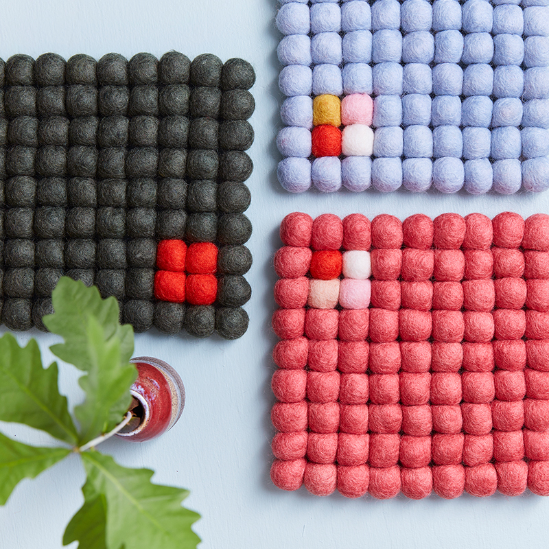 Square trivets of 100% wool - Dark gray, light blue and raspberry red, placed next to each other.