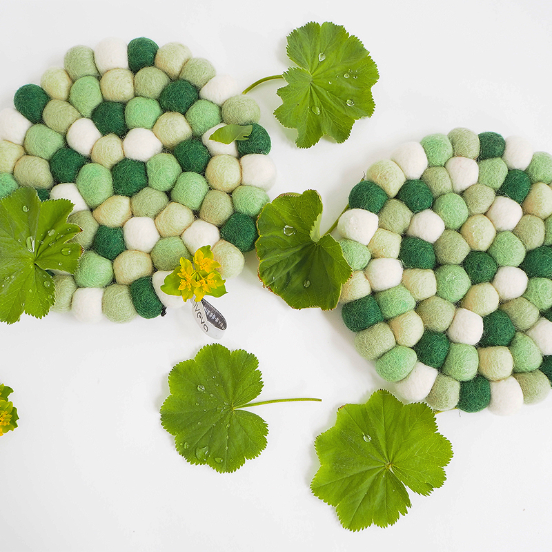 Underlägg i ull i olika blandade gröna färger.