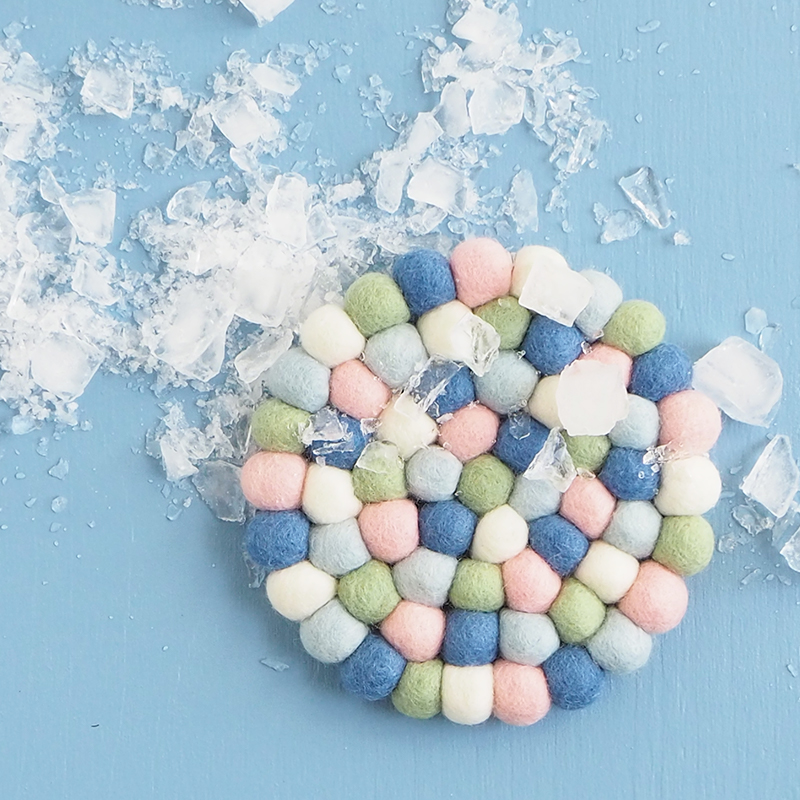 round trivet in a mix of blue, green, pink and white colors, made of wool.
