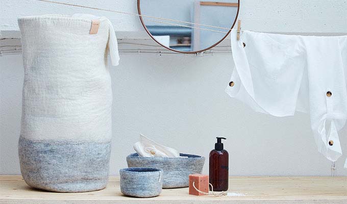Laundry basket in gray and white with laundry items around.