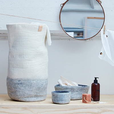 Tvättkorg i grått och vitt med tvättartiklar runt om.