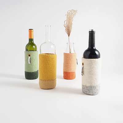 Wool container for bottles in shades of terracotta, ochre, white and green.