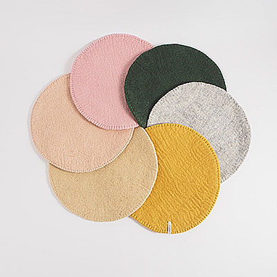 Seat cushions in wool with a stitched edge, lying in a round circle.