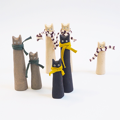 Collection of unique cats made in raw stoneware. White, gray and black. Have a scarf around the neck.