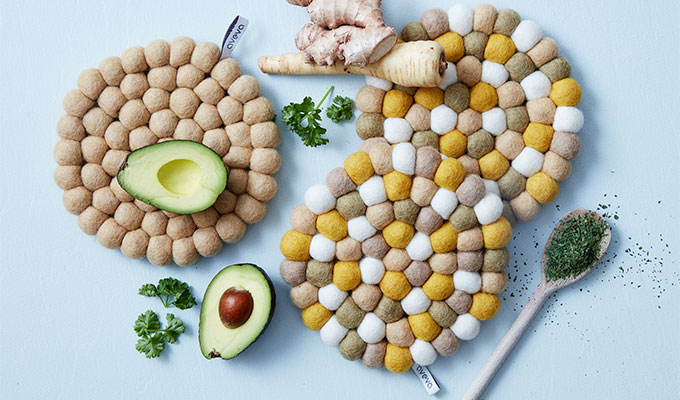 Rund grytunderlägg i ull, i färgerna sand, vit och okra.