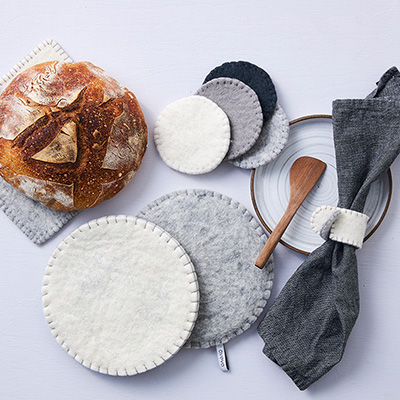 Trivets in round shape in grey, white with coasters in wool in grey, white and black with matching napkin rings