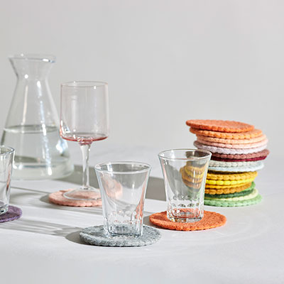 Glass coasters in wool in different colors in a table setting.