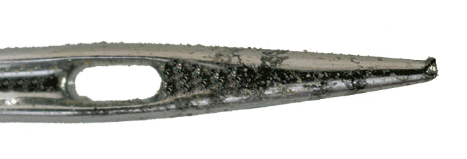 Närbild på en sliten symaskinsnål med böjd och skadad spets