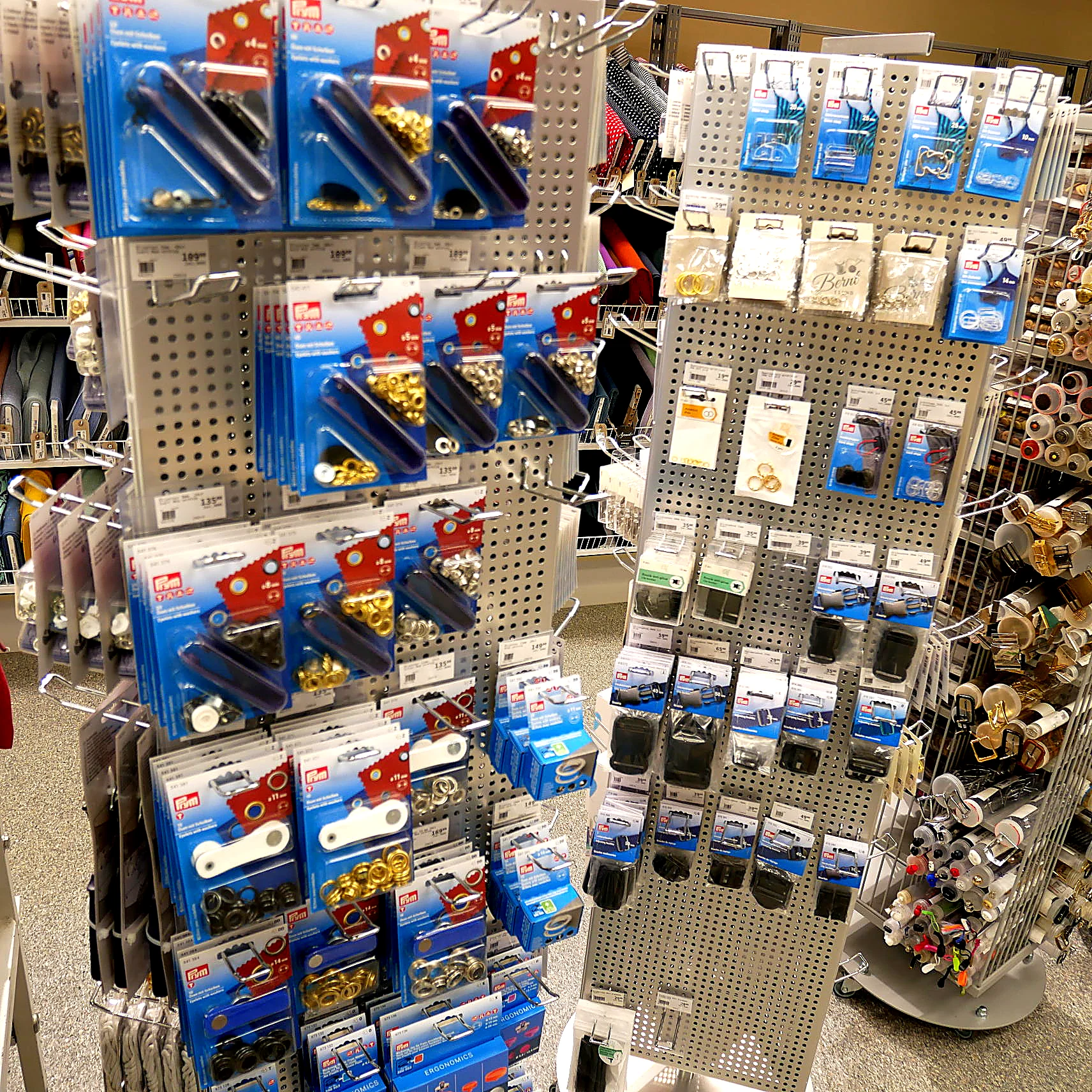 Knappar och tryckknappar i ställ i sybehörsavdelningen