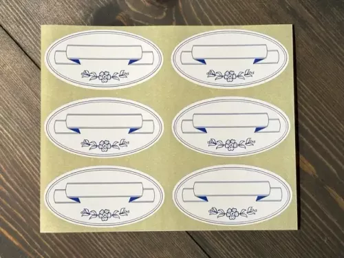 Etikett Oval, Vit med blå banderoll (6 st / ark)