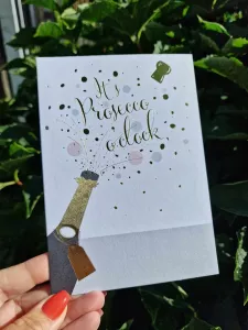 It´s Prosecco o´clock - Kort med en Proseccoflaska som poppar - Pictura