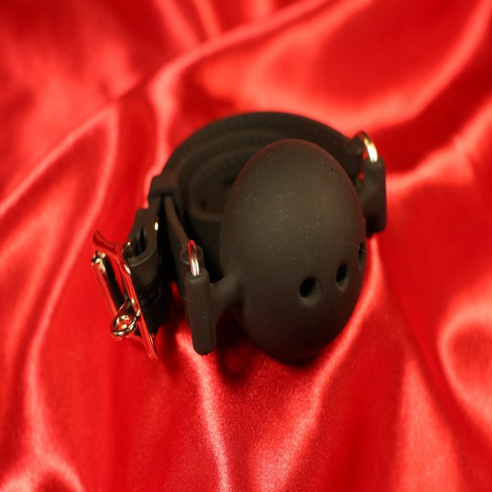 Svart andningsbar silikon boll-gag i storlek L från Chambers of Love. Designad för komfort och säkerhet under längre sessions. Perfekt för BDSM-utlevnad och rollspel. Artikelnummer MWX2122BLL.