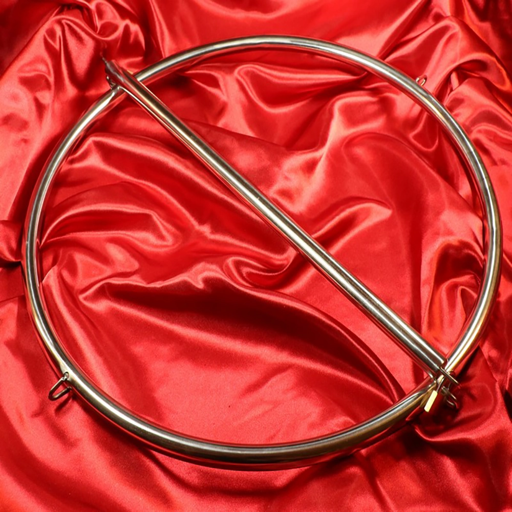 Restriction ring device from Chambers of Love on a red background – designed for a forward-leaning position with a lockable center bar, hanging loops for suspension, and foot restraints for complete restriction.