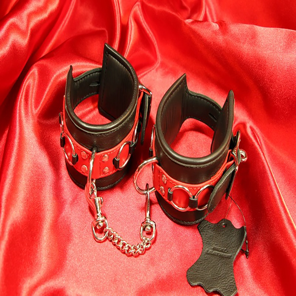 Detaljbild av röd-svarta BDSM-handbojor med karbinhakekedja framtill. En elegant och säker design från Chambers of Love, perfekt för lek och intimitet.