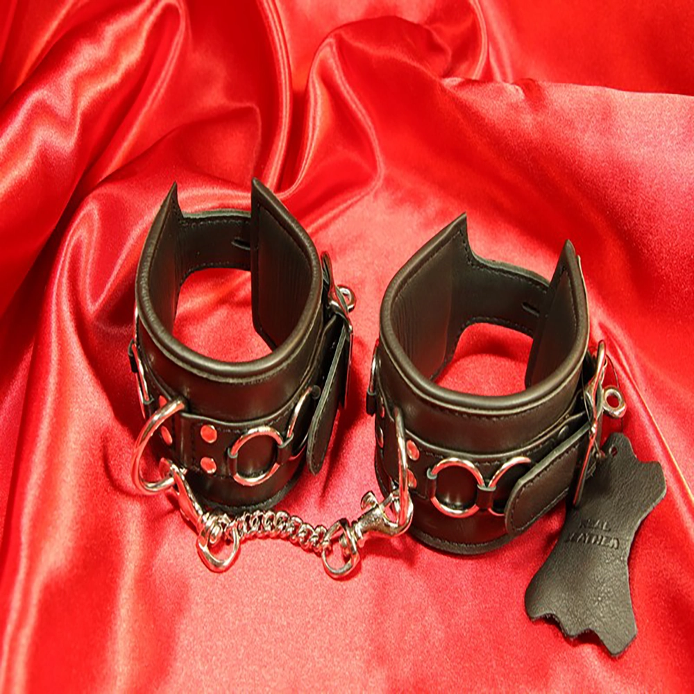 Detaljbild av svarta BDSM-handbojor med karbinhakekedja framtill. En elegant och säker design från Chambers of Love, perfekt för lek och intimitet.