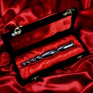 Double-ended steel dildo with beads from Chambers of Love, resting in its black box with red lining, highlighting the luxurious high-gloss metal surface.