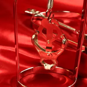 Detail of Japanese nipple clamps with metal stand from Chambers of Love on red satin fabric
