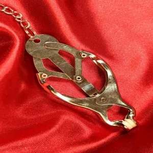 Close-up of Japanese nipple-to-clit clamps with chain from Chambers of Love on red satin fabric