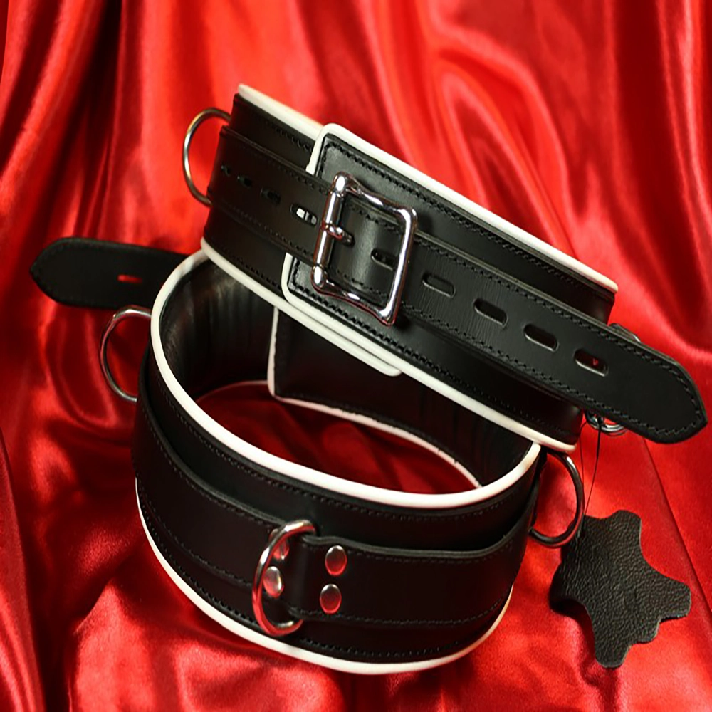 Schwarze, gepolsterte BDSM-Fessel mit weißem Rand von Chambers of Love. Luxuriöses, bequemes und exklusives Design aus unserer Premiumkollektion.