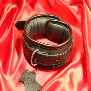 Eksklusiivinen BDSM-kaulapanta mustasta vasikannahasta, pehmeällä, topatulla lampaanvuorilla ja mustalla kanttinauhalla. Vankka, hitsattu D-rengas edessä. Käsintehtyä premium-laatua Chambers of Lovelta.