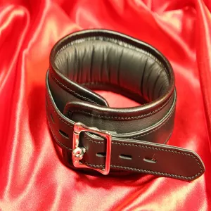 Eksklusiivisen BDSM-kaulapannan takapuoli mustasta vasikannahasta, pehmeällä, topatulla lampaanvuorilla ja mustalla kanttinauhalla. Näyttää lukittavan soljen. Käsintehtyä premium-laatua Chambers of Lovelta.