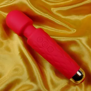 Röd mini magic wand massagevibrator i silikon med mjukt silikonhuvud och greppvänligt skaft, fotograferad på guldfärgad bakgrund; vattentät och uppladdningsbar med 20 vibrationsmönster och 7 hastigheter.