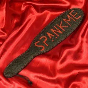 Musta nahkainen läimäyspaddle punaisella tekstillä Spank Me, Chambers of Love, tuotenumerolla XB115. Täydellinen intensiivisiin ja tyylikkäisiin BDSM-leikkeihin.