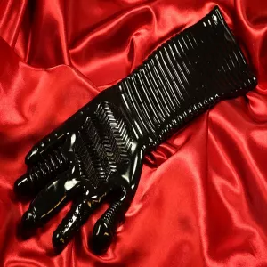 Pleasure Fister texturerad fistinghandske i svart TPR med ribbad underarm och strukturerade fingrar, liggande på rött tyg från Chambers of Love