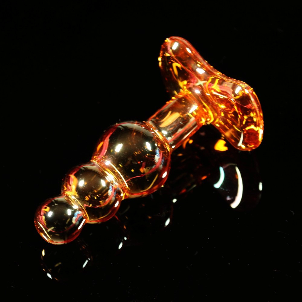 Three-bead glass anal plug from Chambers of Love, photographed lying down. Elegant and sleek design for pleasure and precision.