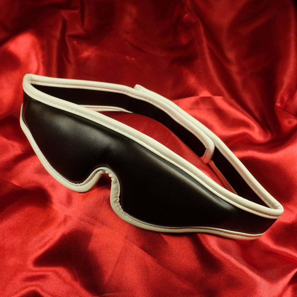 Framsida av vadderad ögonbindel med vit kant i PU-läder från Chambers of Love.