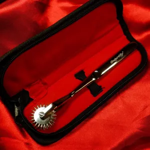 Three-row Wartenberg wheel from Chambers of Love, resting in its case, highlighting the satin-polished finish and clinical medical fetish aesthetic.