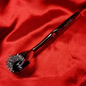 Five-row Wartenberg wheel from Chambers of Love, side view against a red background, clearly showing the wheel profile and satin-polished steel surface.