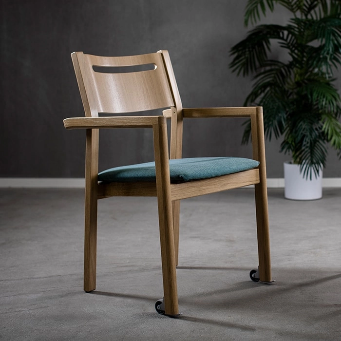 Alma karmstol från Inoff med klädd sits och glidhjul i en miljö.