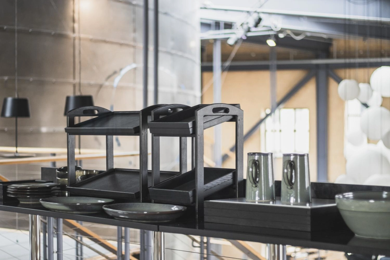 Ställning i svart från Select Concept med stapelbara trälådor och med olika träprodukter.