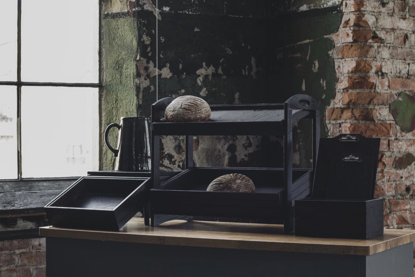 Ställning i svart från Select Concept med stapelbara trälådor och med olika träprodukter.