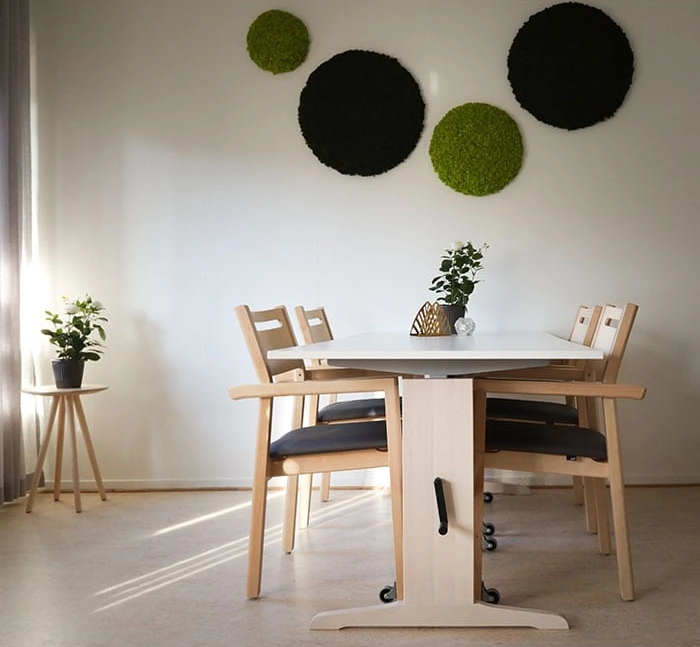 Alma karmstolar från Inoff med klädd sits och glidhjul ihop med Ester bord i en miljö.