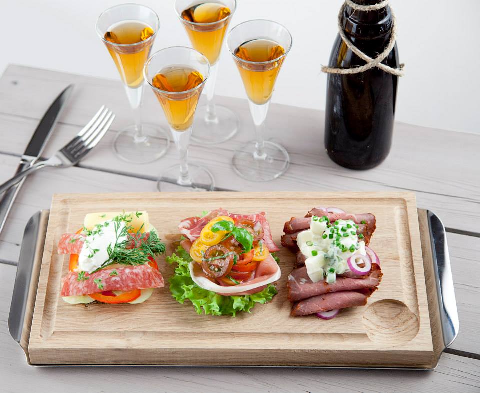 Fiore snapsglas på fot i klassisk design från Bormioli Rocco ihop med planksteksbräda med rostfritt underlägg.