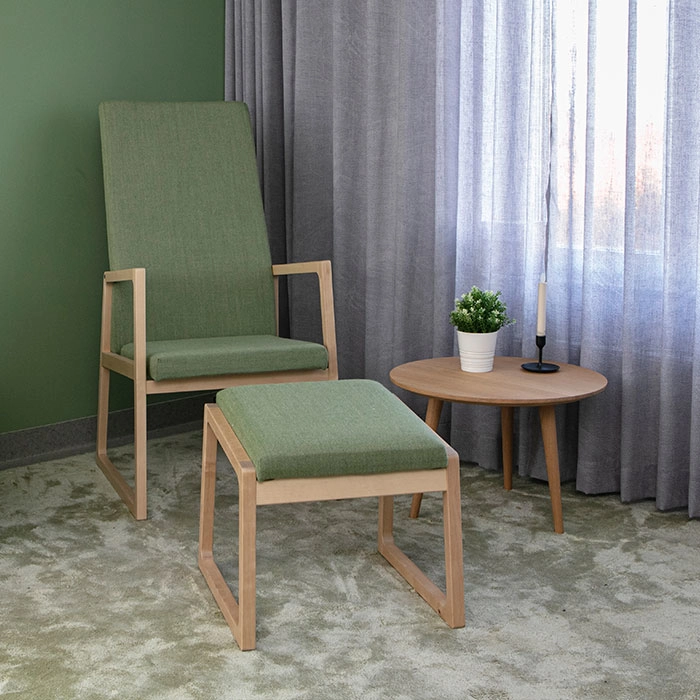 Saga fåtölj med hög rygg ihop med fotpall från Inoff i en miljö.