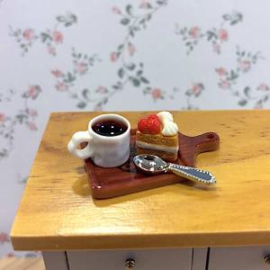 Kaffekopp m kaffe, tårtbit, sked på bricka