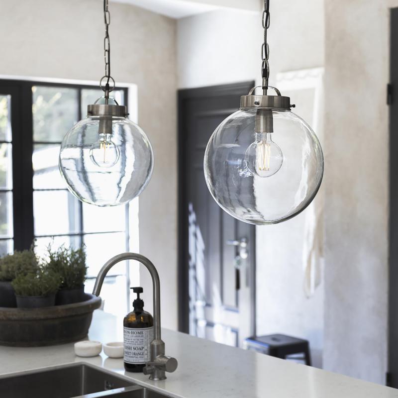 två stycken lampor som glasglober hänger över diskbänk