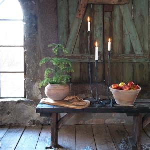 svarta smidesljusstakar i tre stycken olika längder står på ett bord med tända ljus