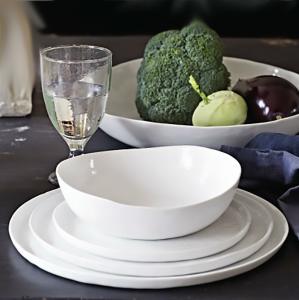 vit tallrik med vit skål ovanpå står på ett bord