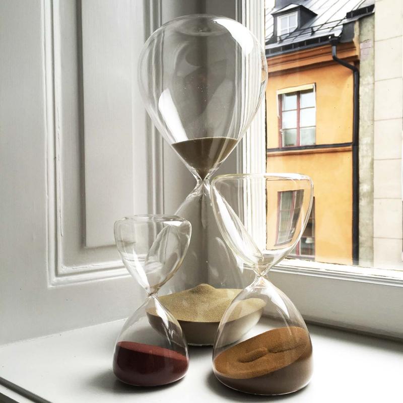 timglas med färgad sand stående i ett fönster