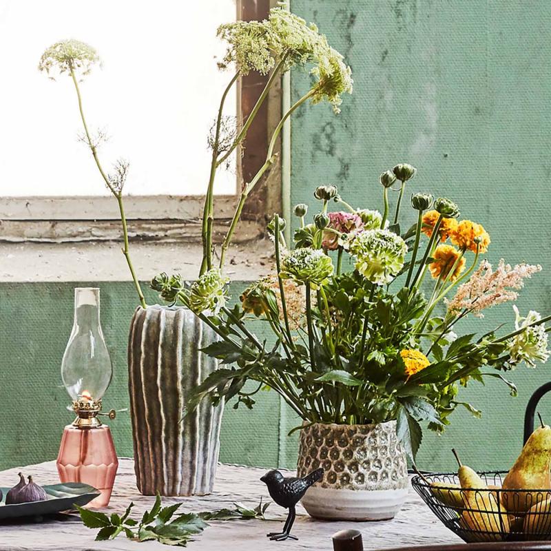 grön vas på ett bord med blommor i
