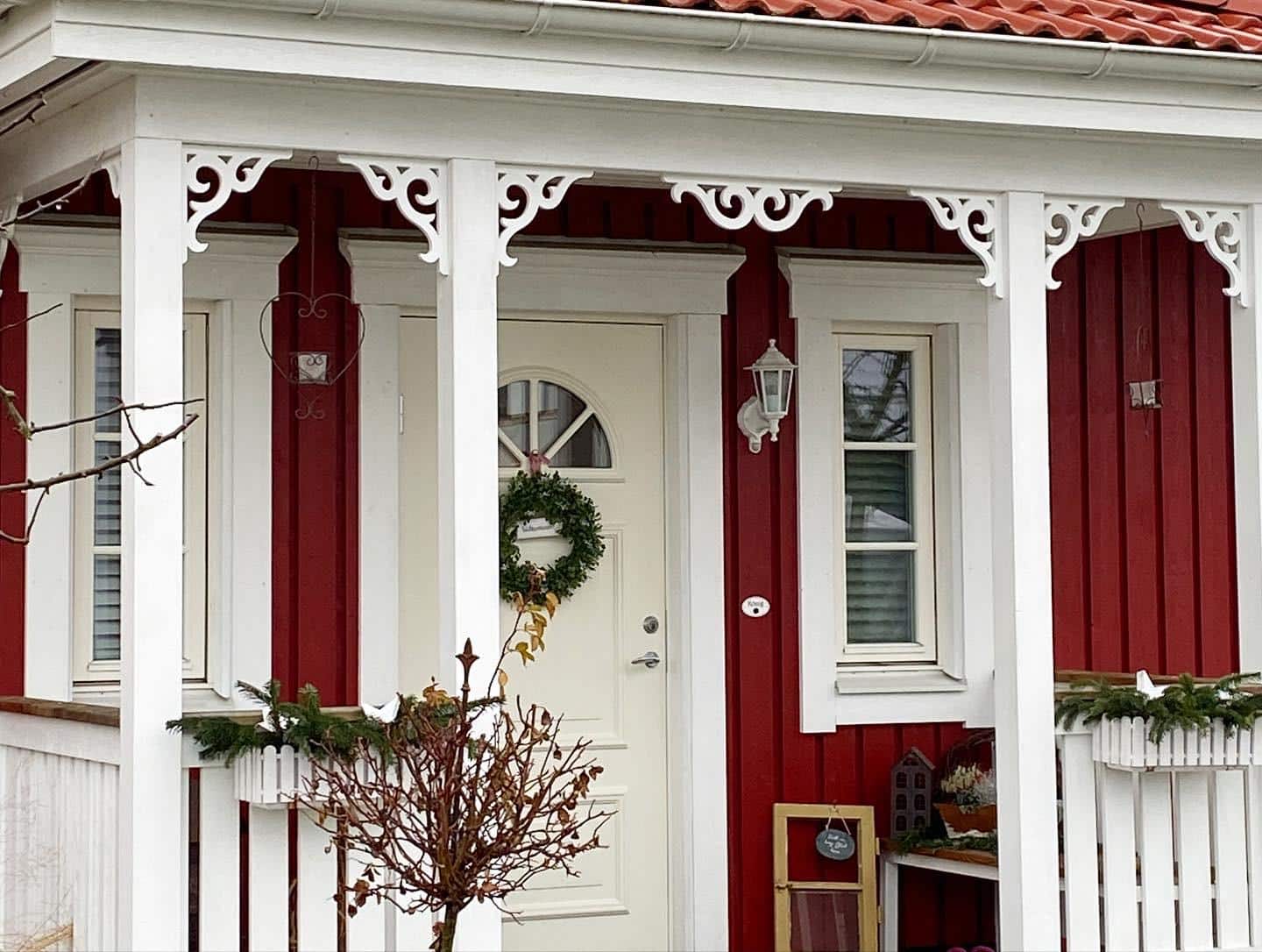 A beautiful Swedish porch with decorative ornaments and wooden brackets - painted in red and white.